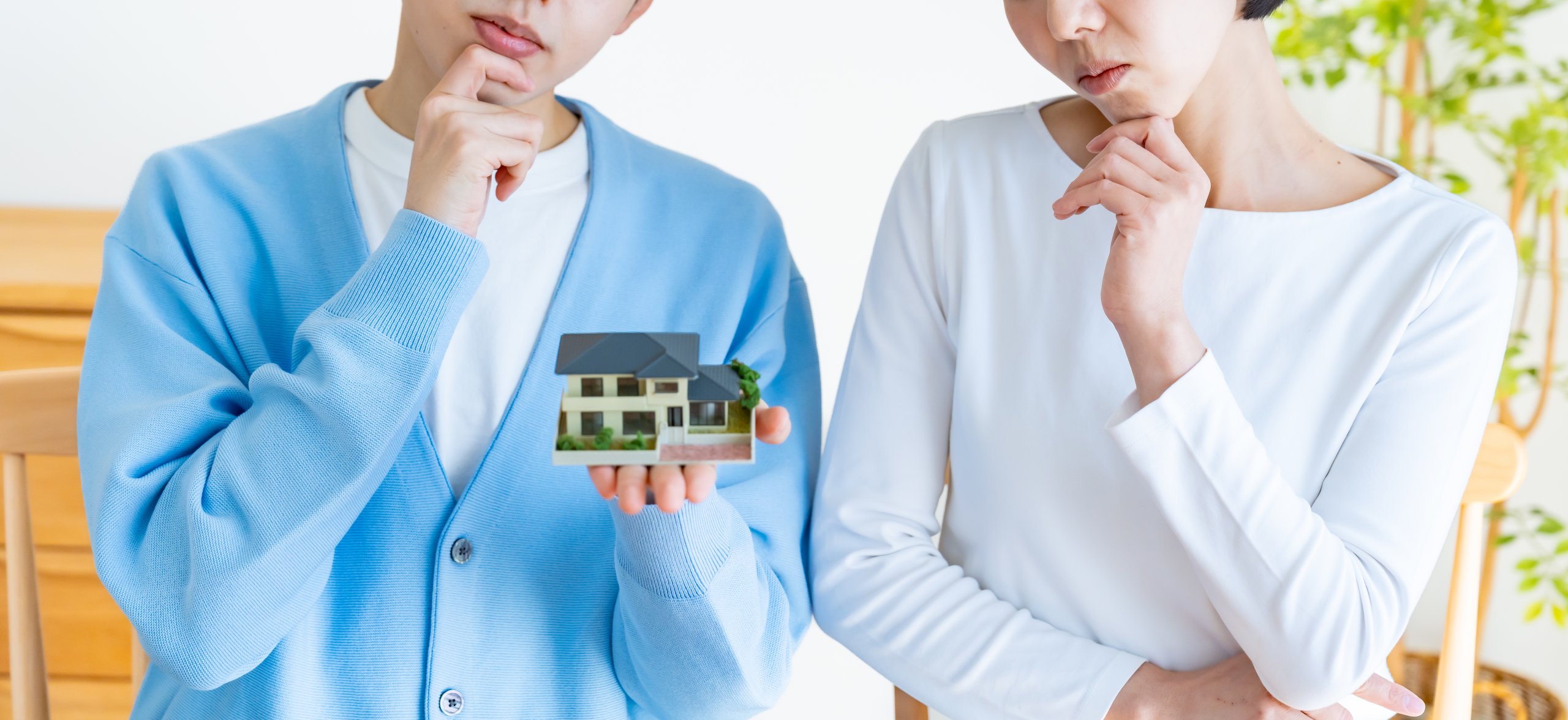 住宅の模型を見ながら真剣に悩んでいる夫婦