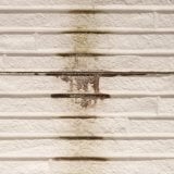 雨だれによる黒ずんだ汚れが付着し、目地の劣化が見られる白い外壁