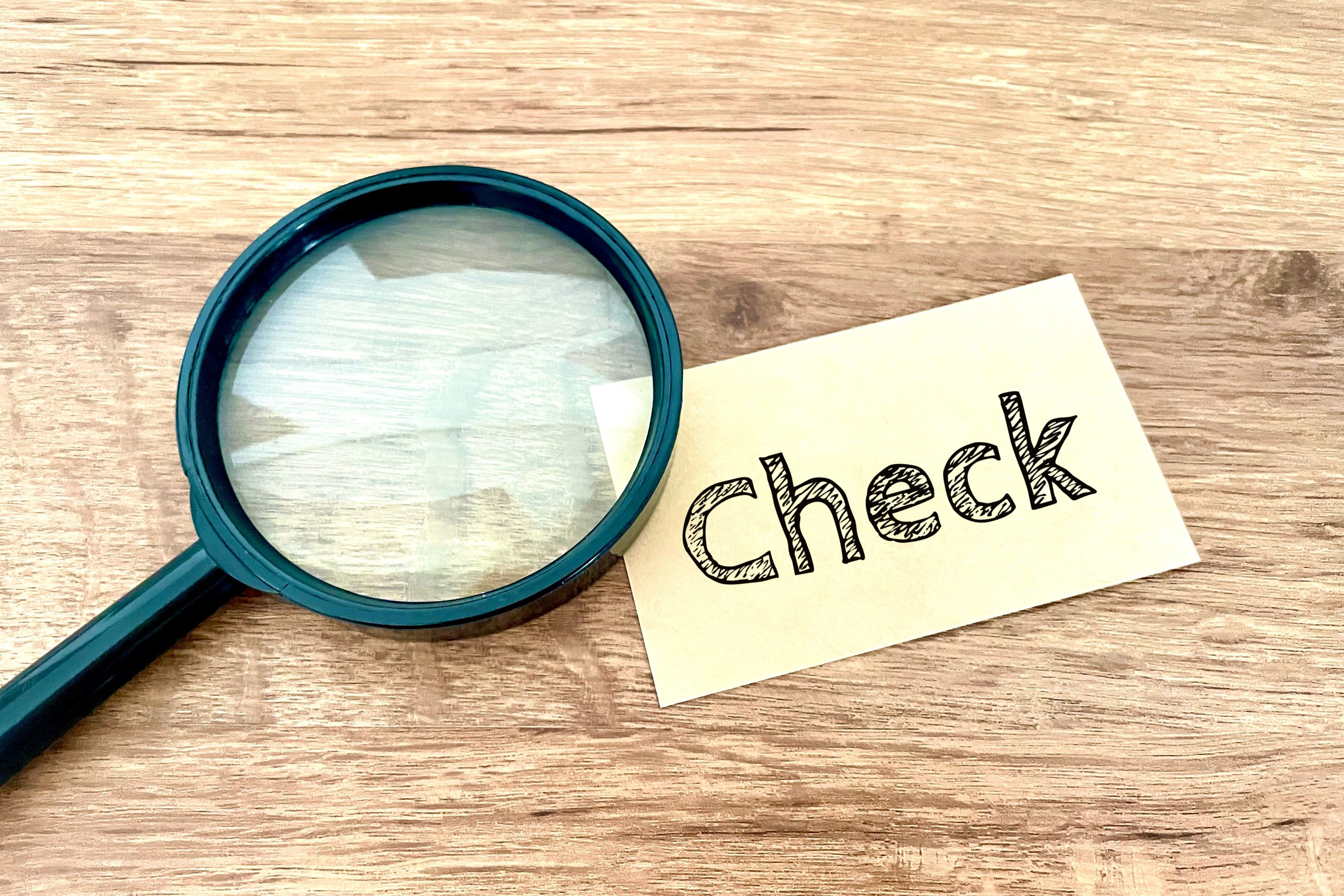 「check」と書かれたメモ用紙と、その上に置かれた虫眼鏡